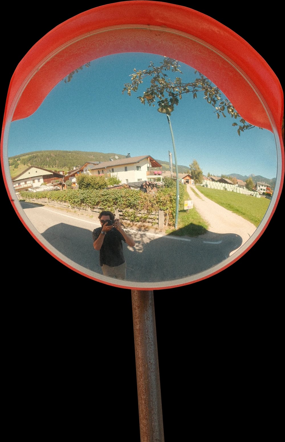 Quentin se photographie dans le reflet d'un miroir rond installé dans la rue
